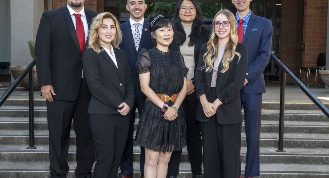 A group of about 8 students pose on the steps of a staircase outdoors